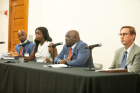 Four people in professional dress seated behind a table with microphones in front of them, speaking on a panel about the Cook County courts.