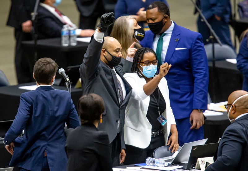 State Rep. Justin Slaughter, center, holds up his fist while wearing a black glove after the SAFE-T Act passed the Illinois House.